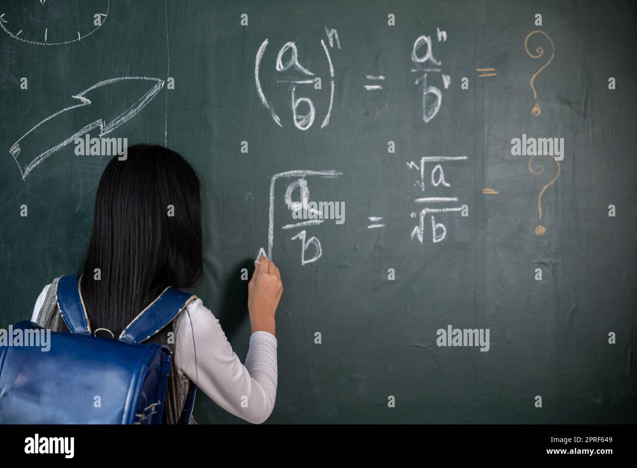 Rückansicht eines Schulmädchens auf Naturwissenschaftsunterricht im Klassenzimmer. Schreib eine Antwort an die Tafel Stockfoto