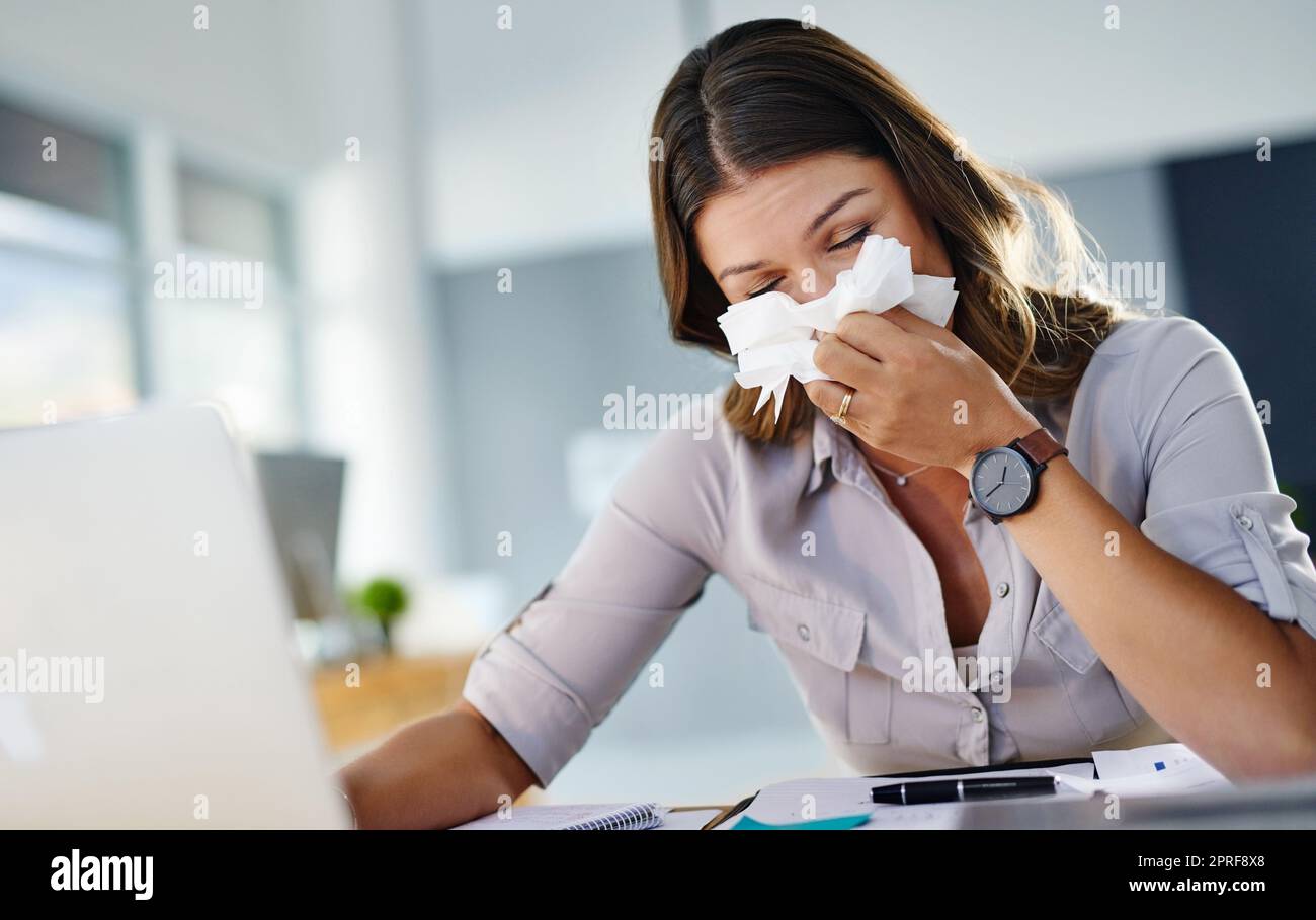 Mir die ganze Zeit die Nase blasen zu müssen, lenkt ab. Eine Geschäftsfrau, die in ihrem Büro arbeitet und an Allergien leidet. Stockfoto