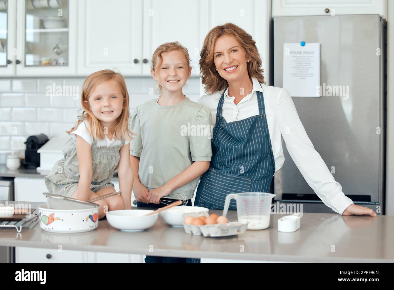 Im Oma-Haus gibt es immer etwas leckeres zu kochen. Porträt einer Großmutter, die mit ihren beiden Enkelinnen zu Hause backt Stockfoto