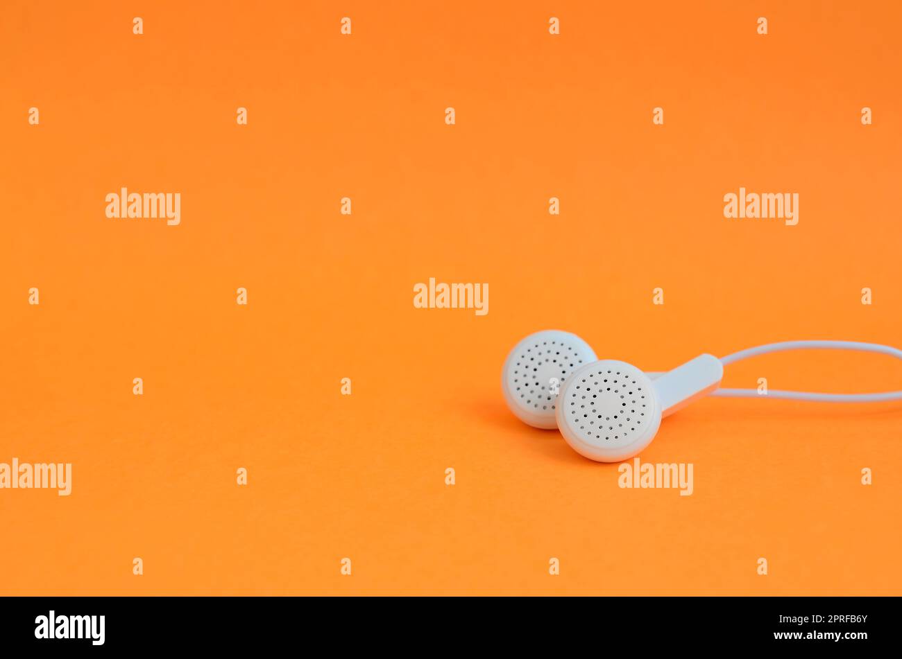 Weißes modernes Kopfhörer liegen auf einem hellen orange hinterlegt. Eine Vorlage für Musik Fans Stockfoto