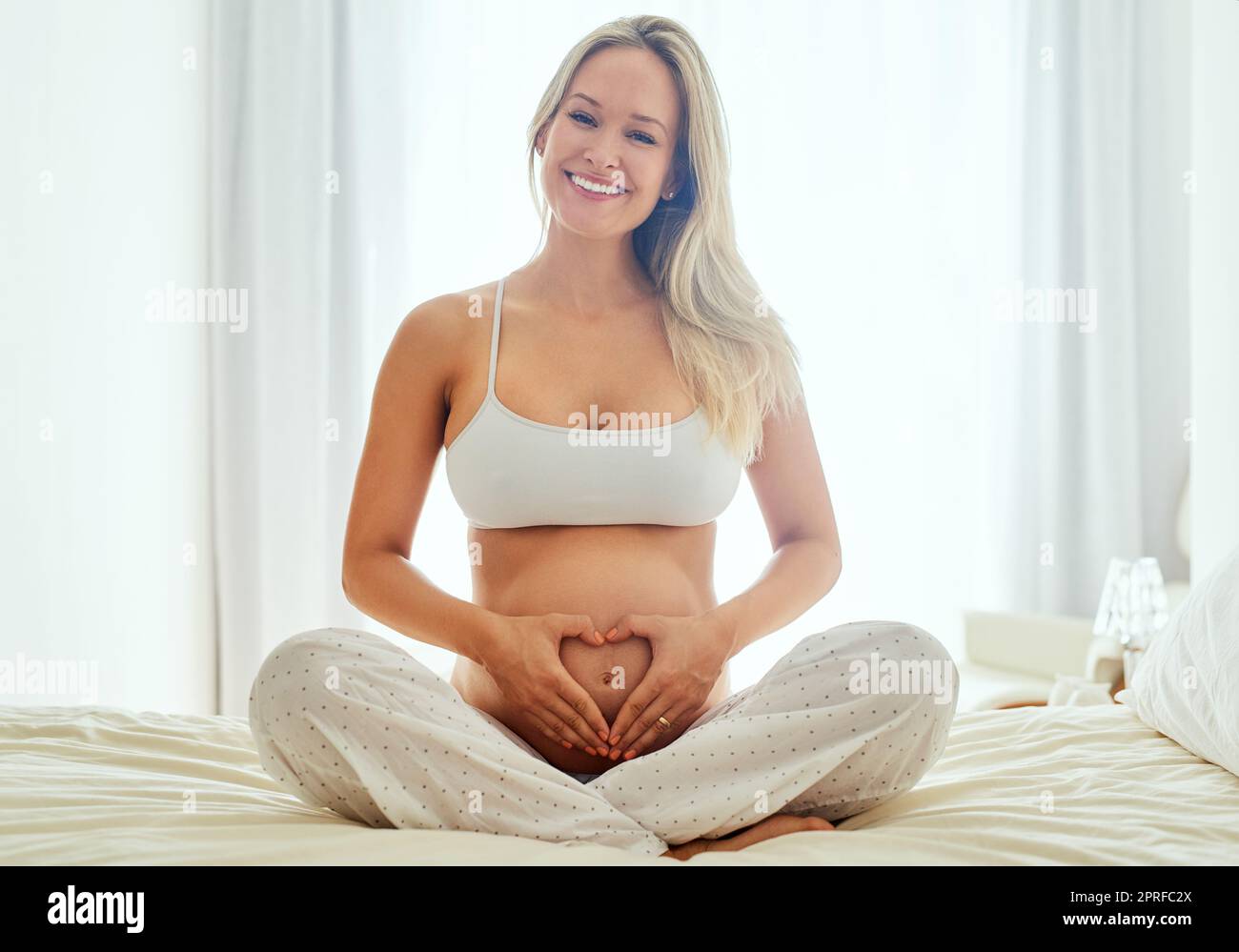 Ich habe nichts als Liebe für meine Baby-Beule. Eine Schwangere hält ihren Bauch mit ihren Händen bilden eine Herzform. Stockfoto