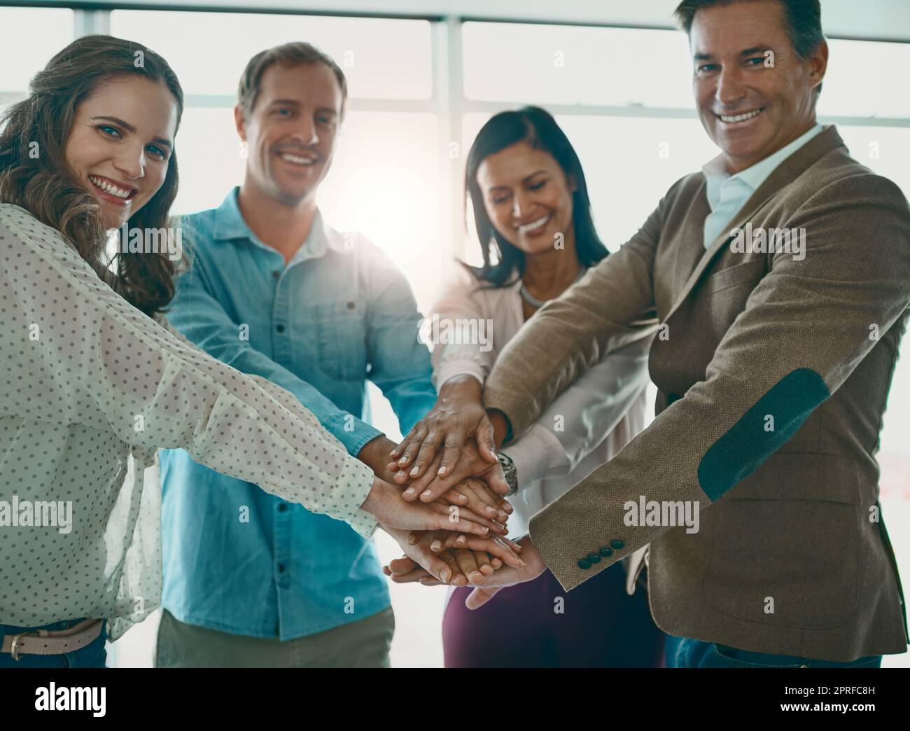 Teamarbeit bringt Sie weit in ein Unternehmen. Eine motivierte Gruppe von Geschäftsleuten, die mit den Händen im Büro stehen. Stockfoto
