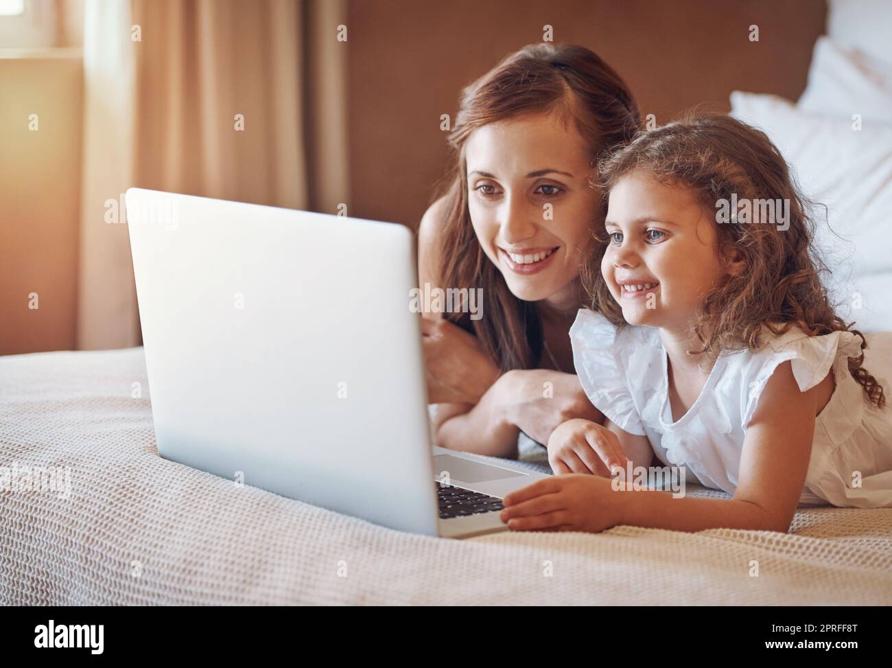 Filmzeit mit Mama. Eine Mutter und ihre kleine Tochter benutzen zu Hause einen Laptop. Stockfoto