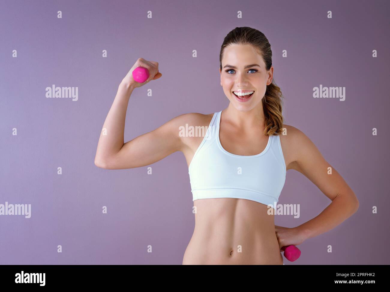 Heben Sie Gewichte dann Gewicht zu verlieren. Studioaufnahme einer gesunden jungen Frau, die Hanteln vor einem violetten Hintergrund hält. Stockfoto