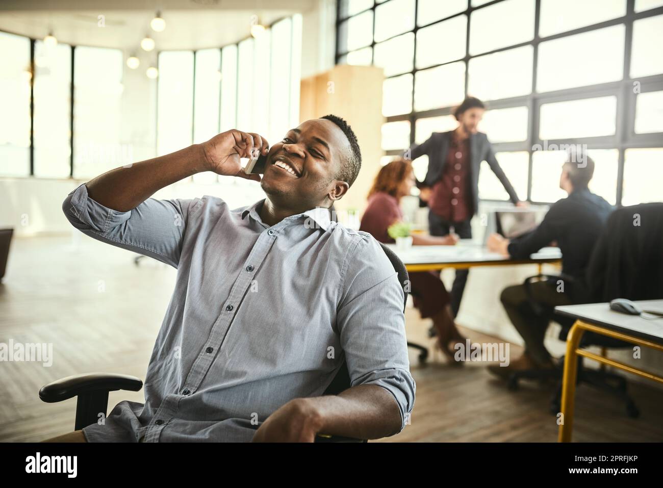 Ich habe es in kürzester Zeit geschafft. Ein hübscher junger Geschäftsmann, der im Büro auf seinem Handy spricht. Stockfoto