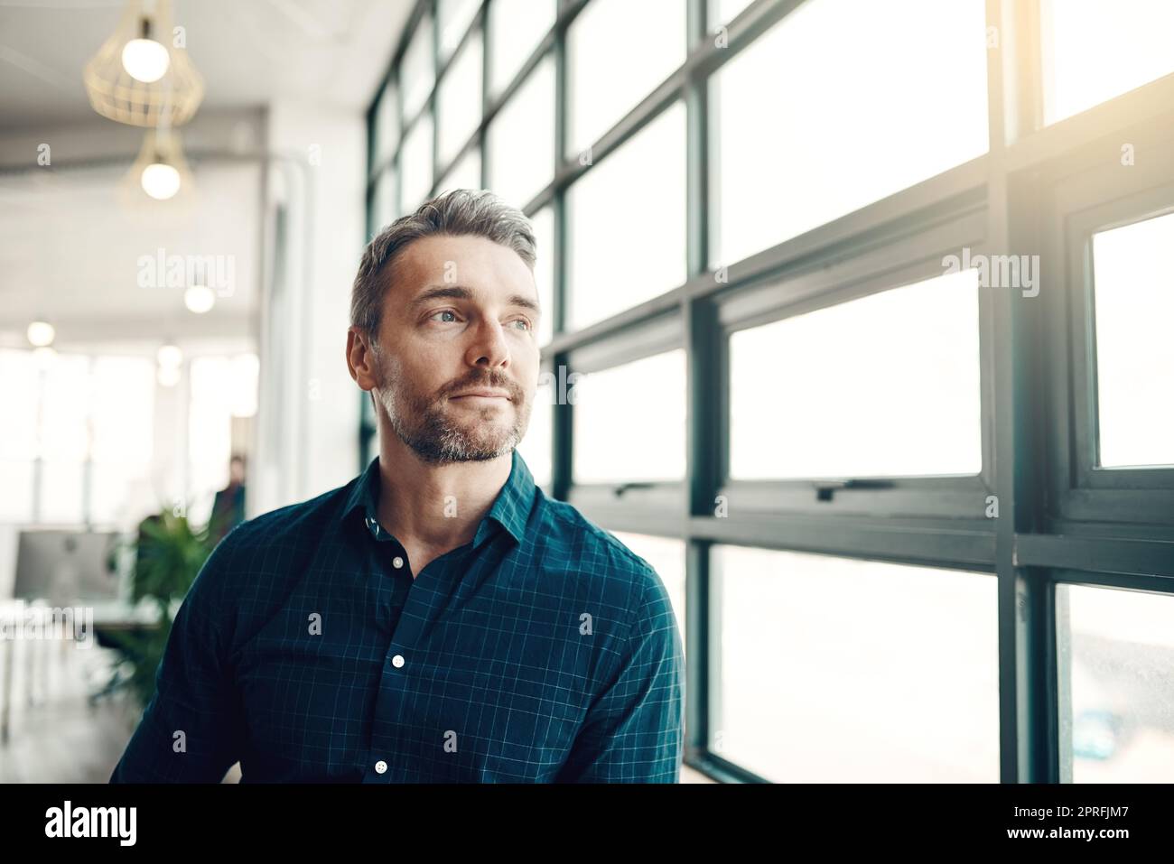 Die Gelegenheit hängt nicht herum, auch nicht Sie. Ein reifer Geschäftsmann, der nachdenklich aus einem Bürofenster schaut. Stockfoto