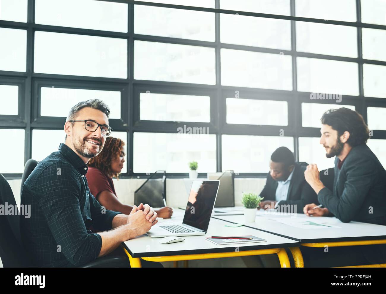 Innovation ist das, was wir anstreben. Beschnittenes Porträt eines reifen Geschäftsmannes, der mit seinen Kollegen im Büro an einem Schreibtisch arbeitet. Stockfoto