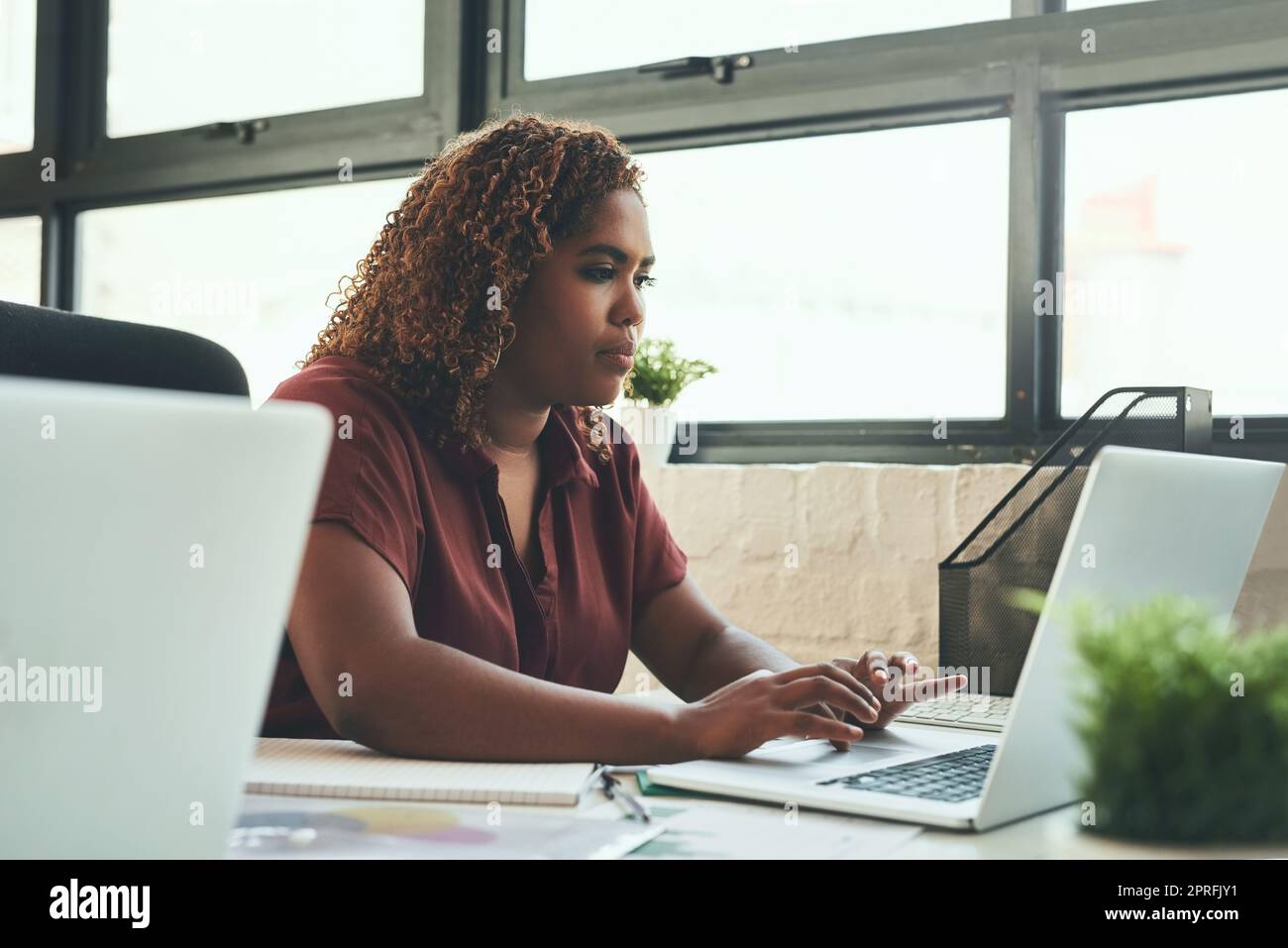 Ihre Designkompetenz ist unbestritten: Eine junge Geschäftsfrau, die im Büro an ihrem Laptop arbeitet. Stockfoto