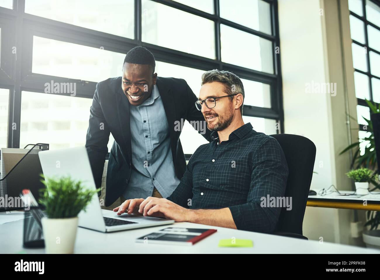Das sieht toll aus. Zwei Geschäftsleute, die in ihrem Büro an einem Laptop arbeiten. Stockfoto