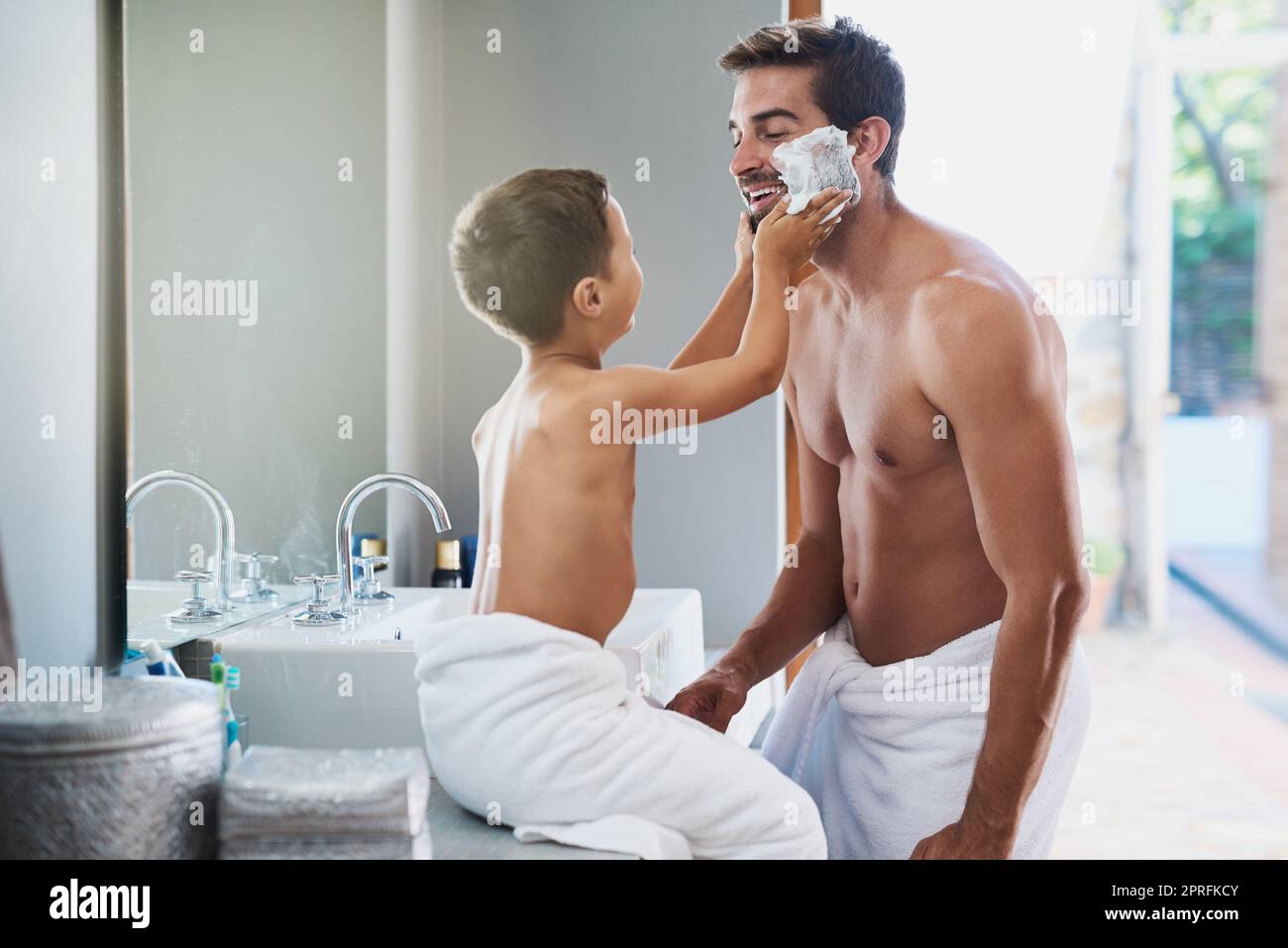 Ein hübscher junger Mann lehrt seinem Sohn, wie man sich im Badezimmer rasieren kann. Stockfoto