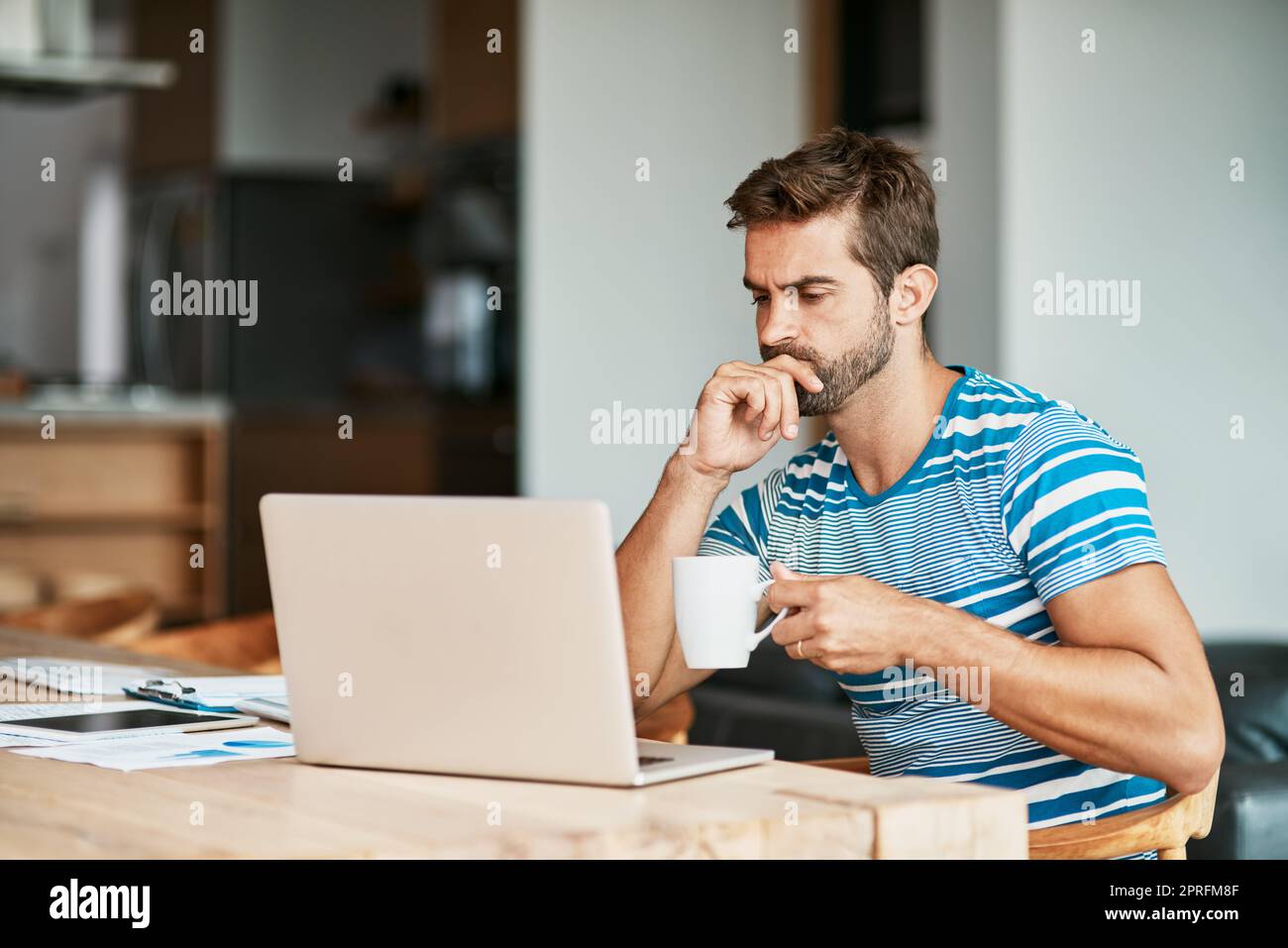 HES hat viel darüber nachzudenken. Ein hübscher junger Unternehmer, der nachdenklich aussieht, während er von seinem Heimbüro aus arbeitet. Stockfoto