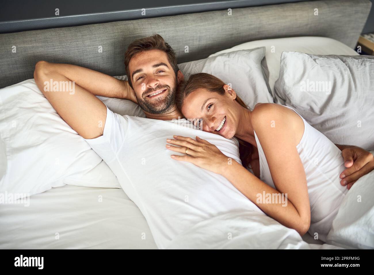 Wir alle lieben ein bisschen Faulheit. Ein glückliches junges Paar, das sich zu Hause im Bett entspannt. Stockfoto