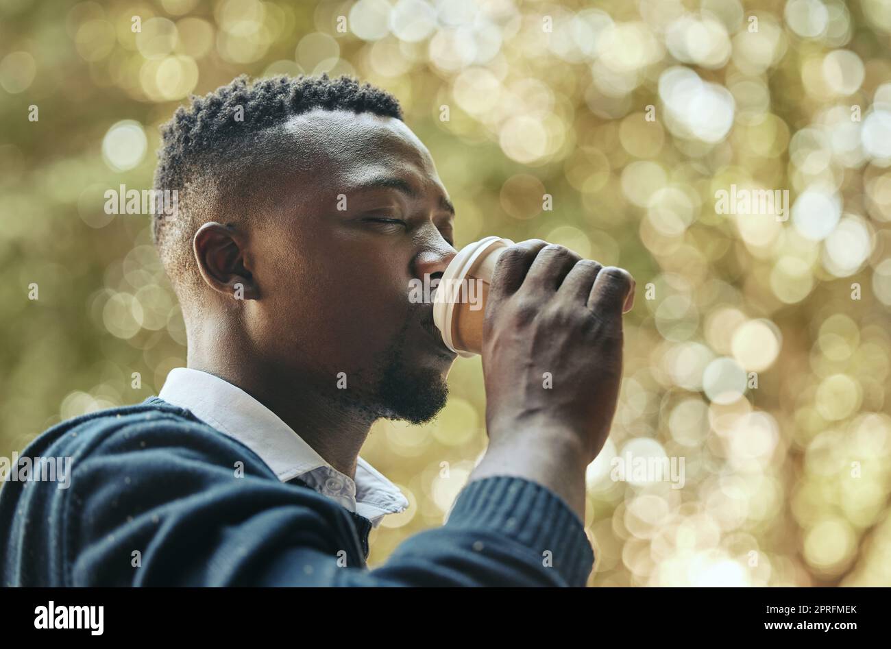 Geschäftsmann mit Kaffeetasse in einem Park mit Bäumen, Natur und Bokeh-Hintergrund. Ruhiger schwarzer Mann, professioneller Mitarbeiter oder Mitarbeiter in einer Kaffeepause mit Espresso am Morgen vor der Arbeit Stockfoto