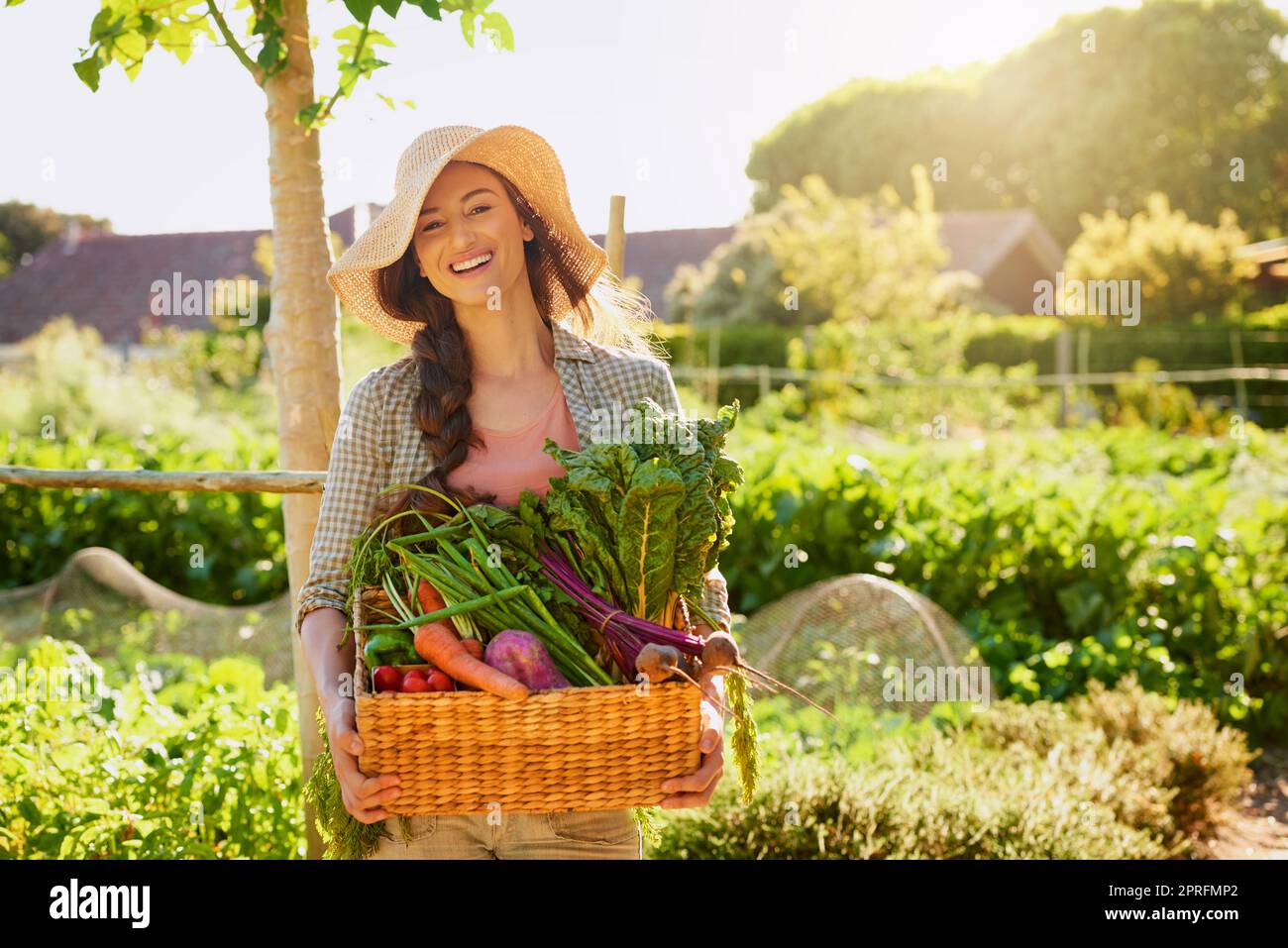 Von Mutter Natur selbst gewachsen. Porträt einer jungen Frau, die einen Korb mit frisch gepflückten Produkten in einem Garten trägt. Stockfoto