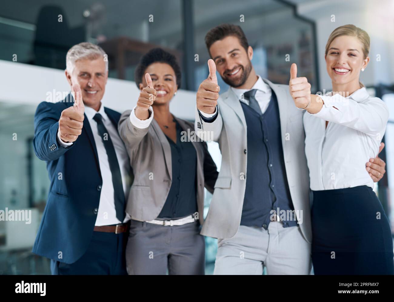Geschäftige Geschäftstage. Ein motiviertes Geschäftsteam, das Daumen hoch und lächelnd zeigt. Stockfoto