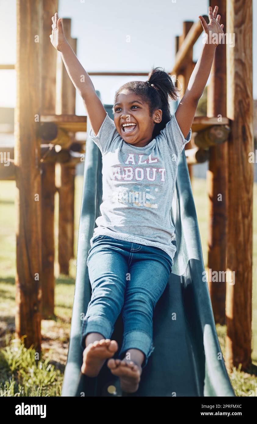 Gleiten Sie in einen Tag voller Spaß. Ein entzückendes kleines Mädchen spielt auf einer Rutsche im Park. Stockfoto