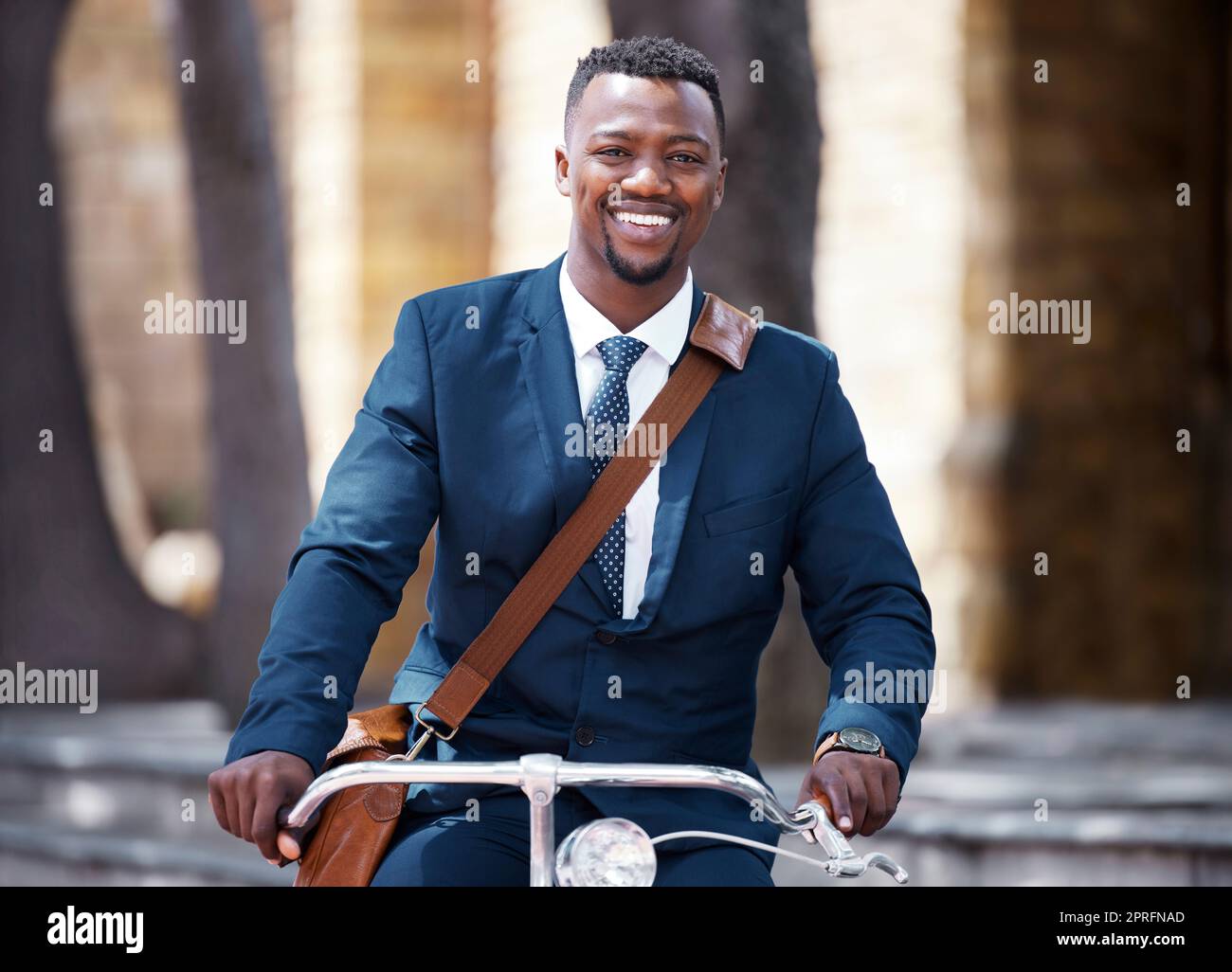 Porträt eines glücklichen Geschäftsmanns auf dem Fahrrad oder Fahrrad auf seiner morgendlichen Reise zur Arbeit in der Stadt. Mitarbeiter, Unternehmer oder Arbeiter auf der Fahrt mit einer Suite und einem Lächeln verringern seine CO2-Bilanz Stockfoto