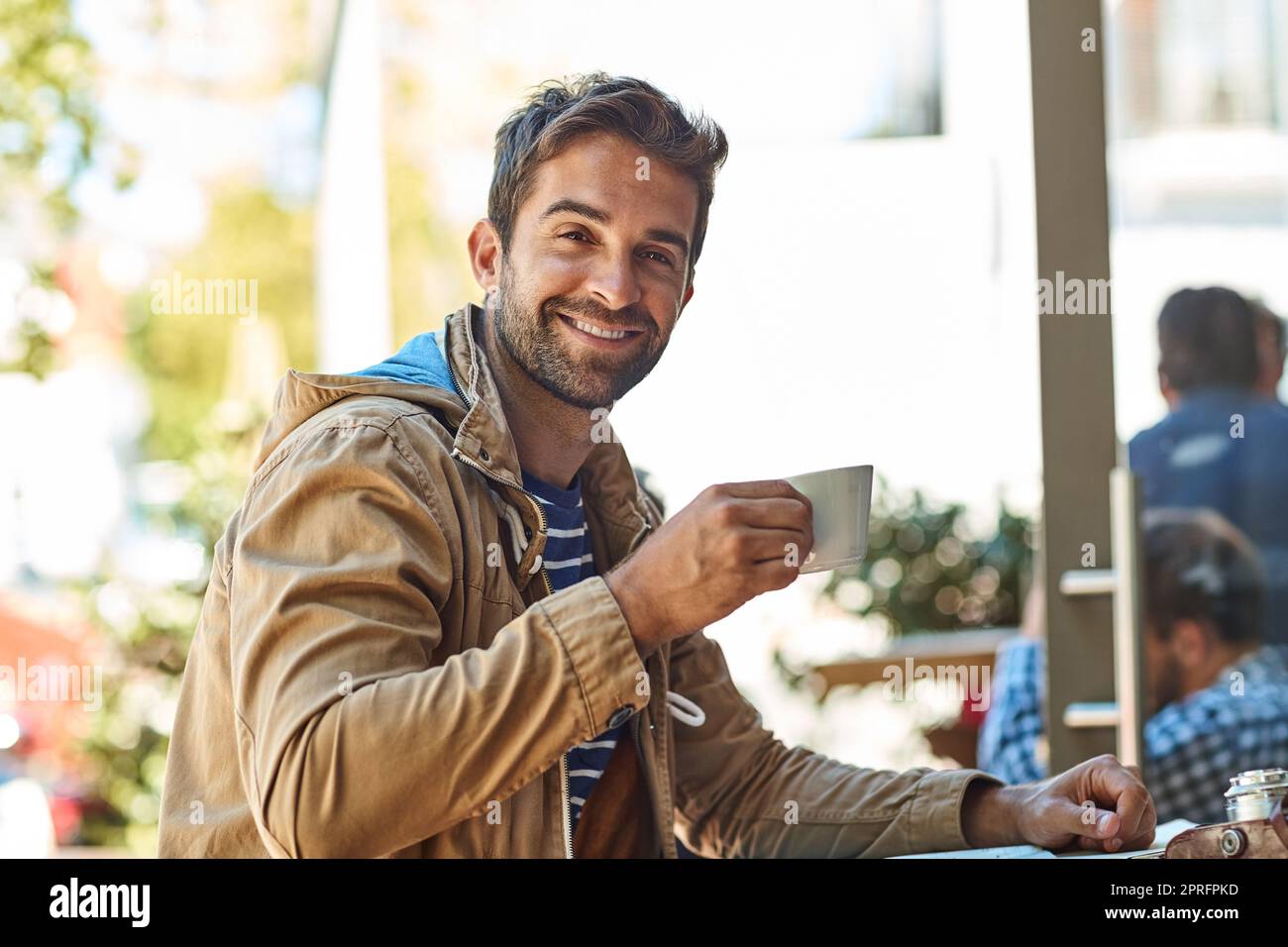 Die heutigen Abenteuer werden stolz von Kaffee gesponsert. Porträt eines entspannten Touristen, der eine Tasse Kaffee in einem Straßencafé genießt. Stockfoto