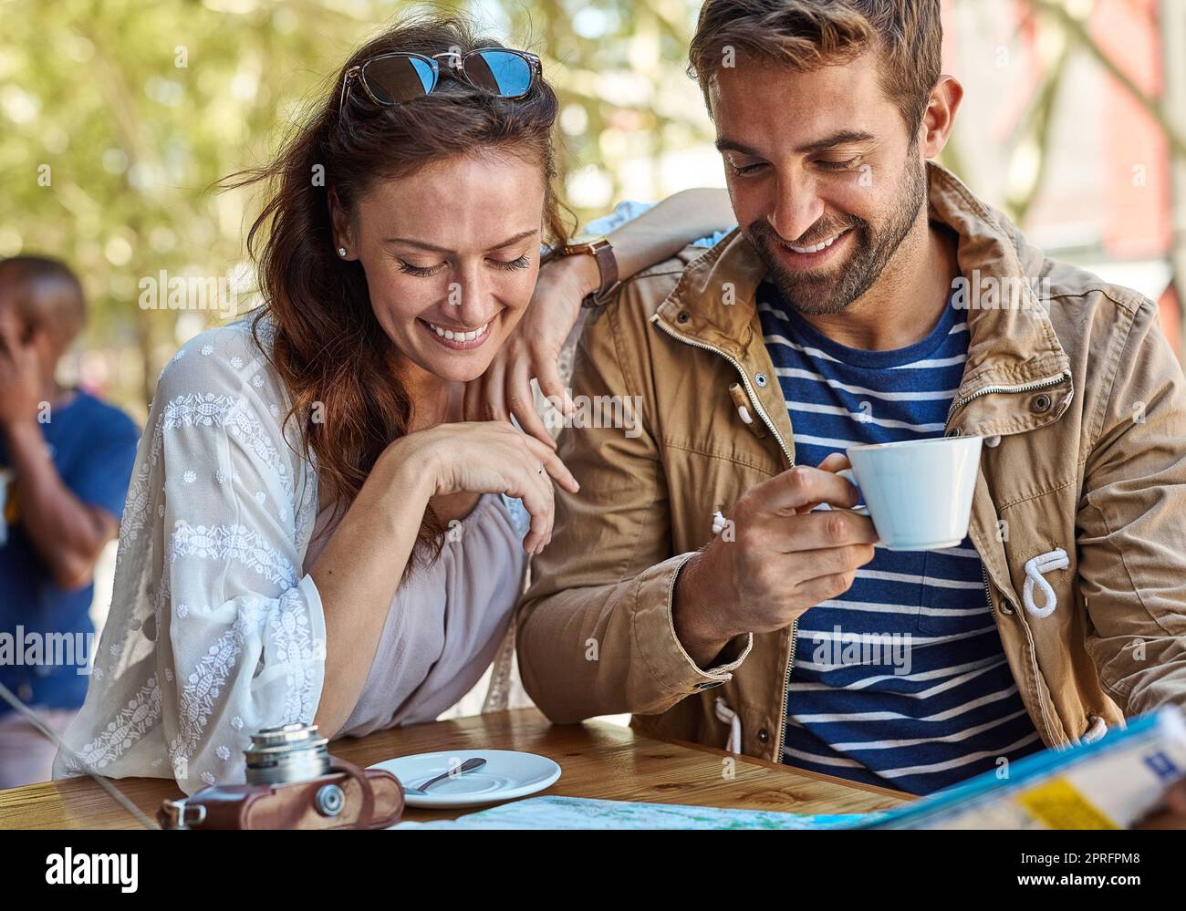Ein glückliches Touristenpaar plante ihren Tag, während es Kaffee in einem Straßencafe hatte. Stockfoto