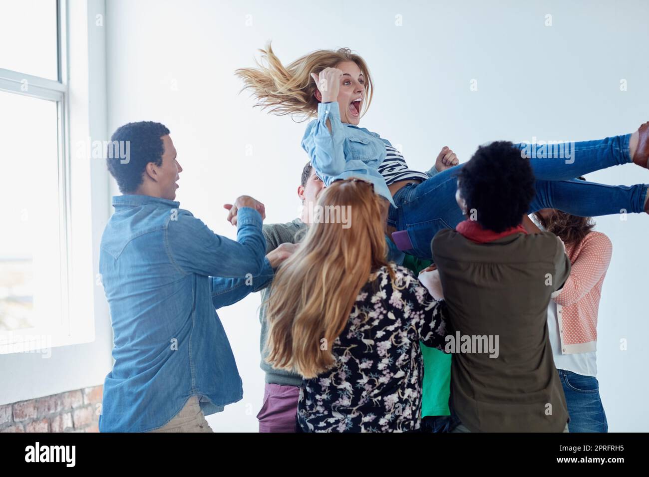 Eine Gruppe von Studenten wirft während des Unterrichts einen anderen Studenten in die Luft. Stockfoto