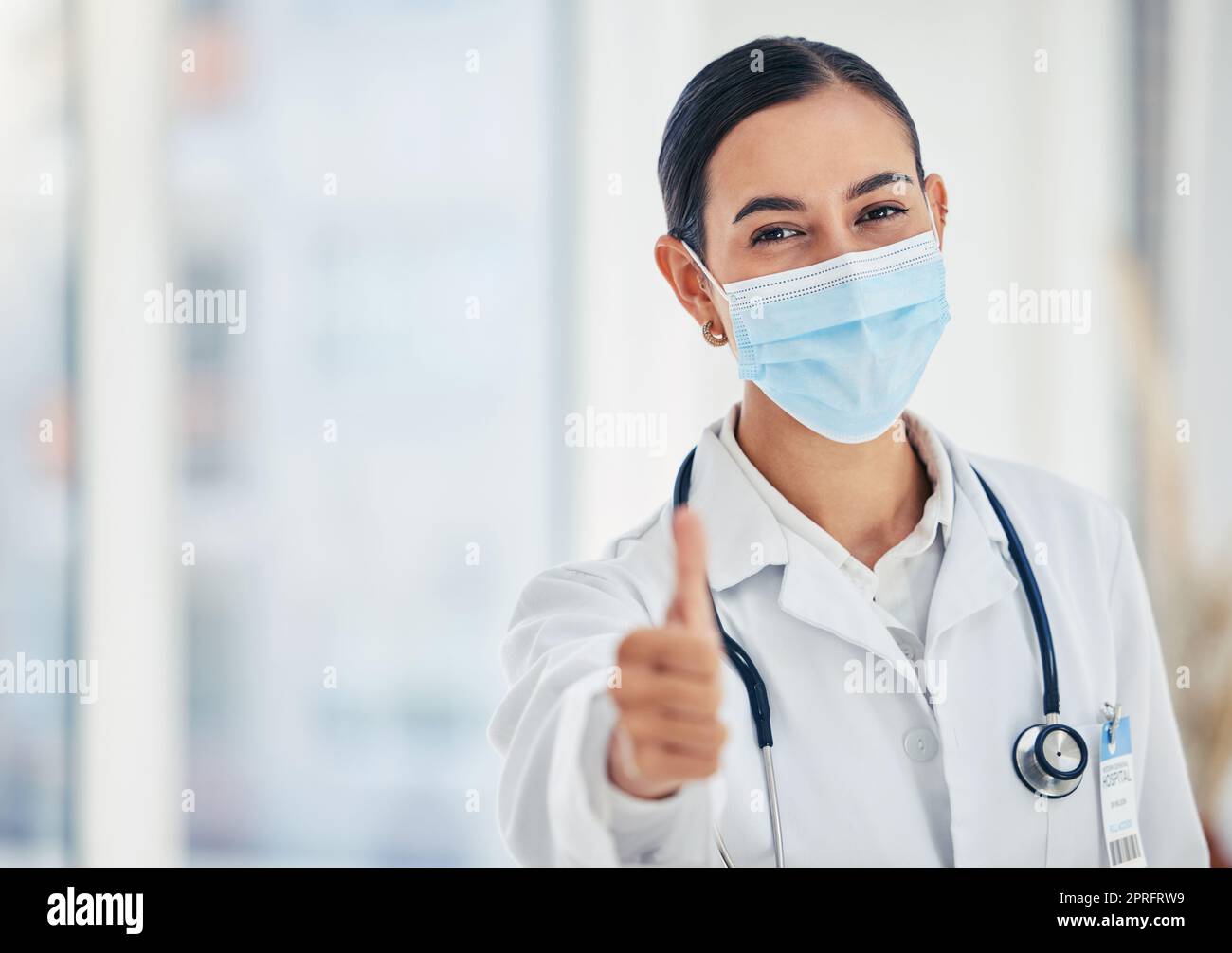 Daumen hoch, Maskenporträt und Arzt in Absprache mit dem medizinischen Verfahren im Krankenhaus. Arzthelferin mit ja Handgeste zur Zufriedenheit mit dem Sicherheitsprotokoll in der Pflegeeinrichtung. Stockfoto