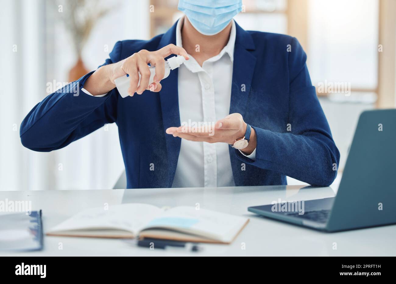 Businesssprühreinigung mit einer covid-Maske während der Arbeit im Büro. Unternehmer reinigen und desinfizieren seine Hände, um die Ausbreitung von Keimen, Korona und Infektionen in der Covid-Pandemie zu verhindern Stockfoto