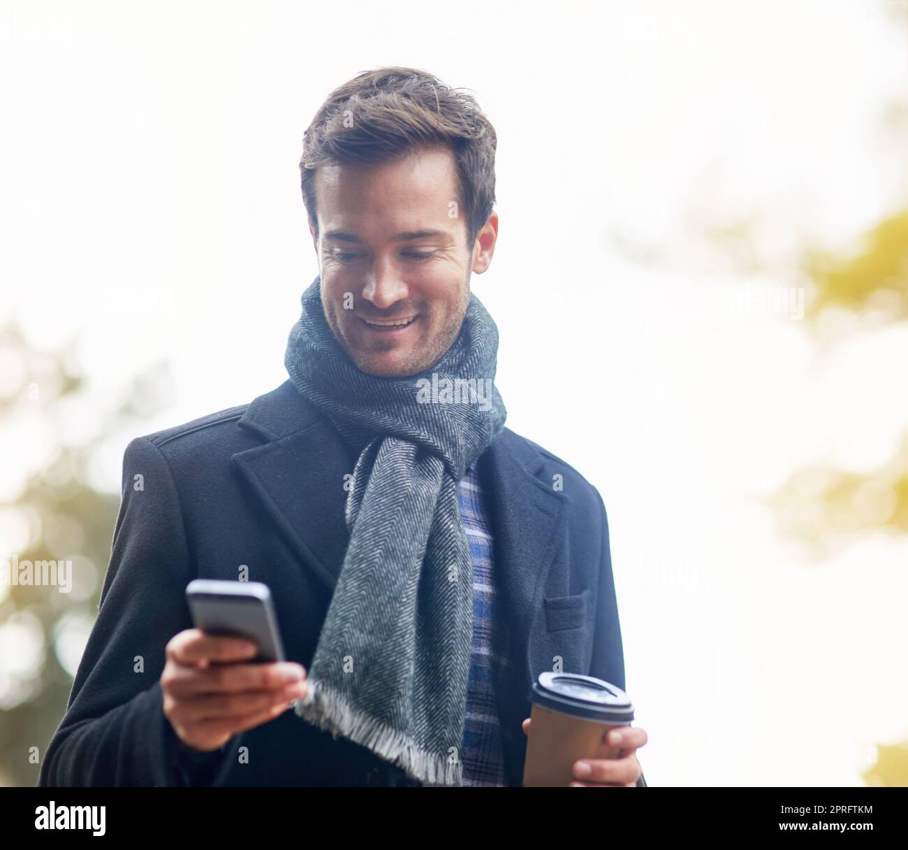 Instant Messaging für Echtzeit-Gespräche. Ein junger Mann, der sein Telefon draußen benutzt. Stockfoto