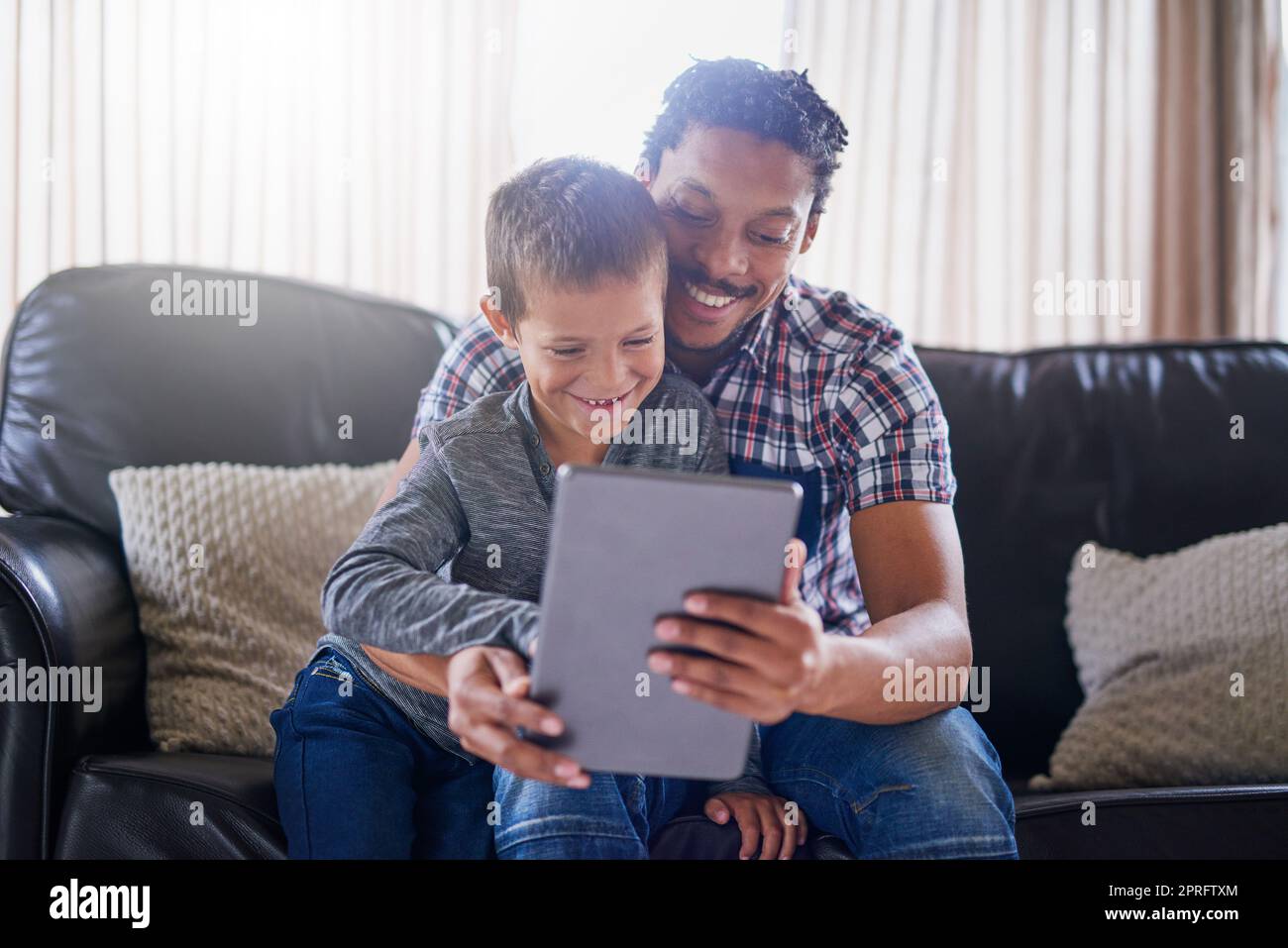 Es gibt immer etwas unterhaltsames online zu sehen. Ein Vater und Sohn mit einem digitalen Tablet zu Hause. Stockfoto