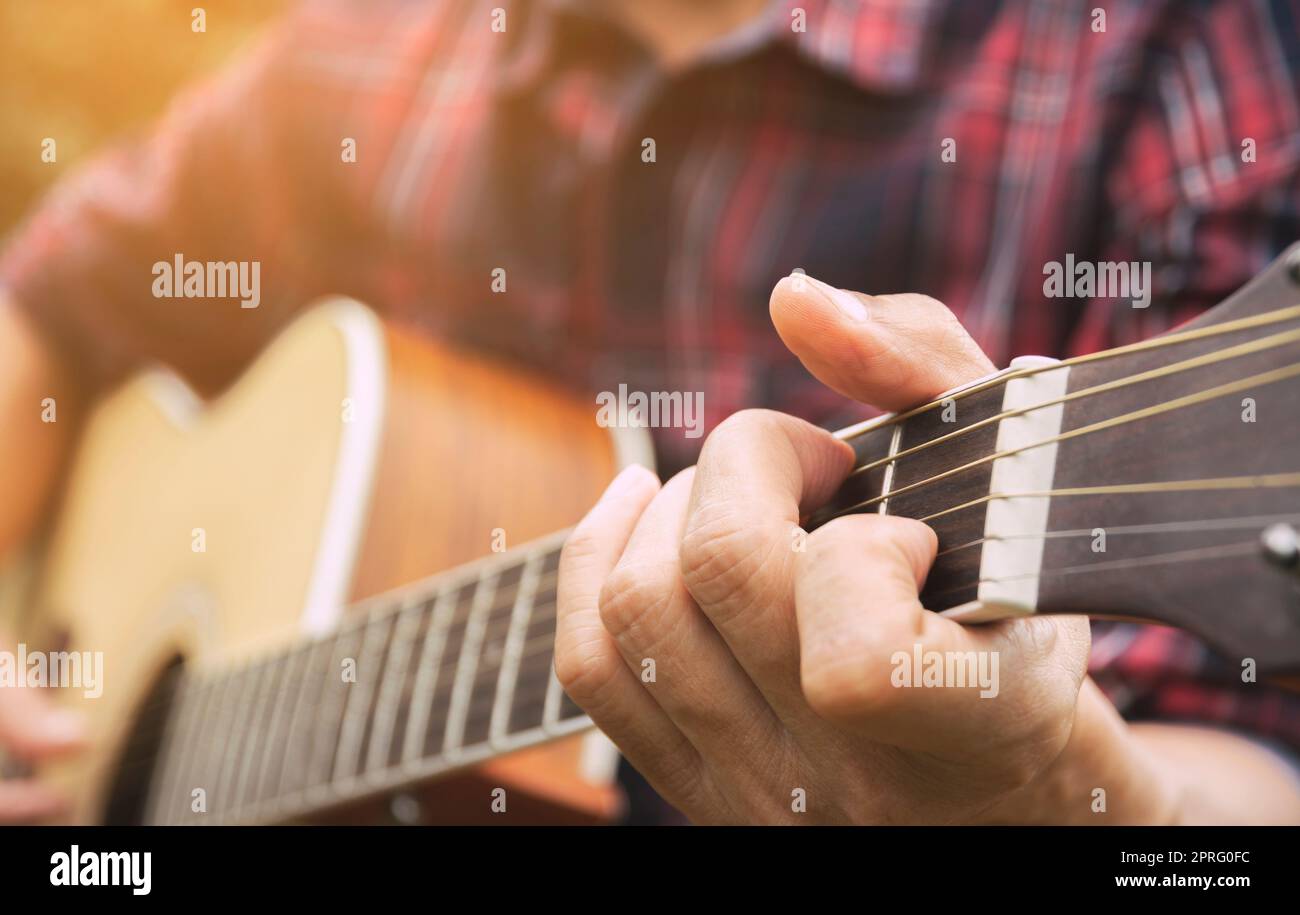 Musiker spielt akustische Gitarre. Nahaufnahme der Hand des Mannes, der Gitarre spielt. Stockfoto