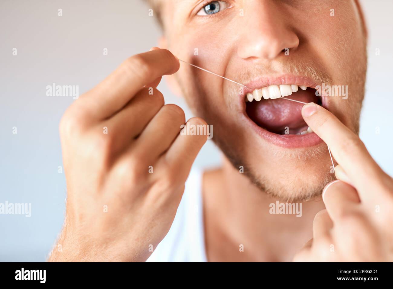 Keime und Plaque sind keine Chance. Nahaufnahme eines jungen Mannes, der zu Hause seine Zähne mit Zahnseide verputzt hat. Stockfoto