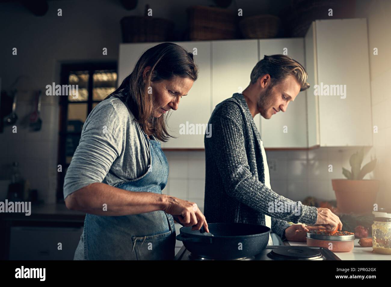 Wie eine Mutter wie ein Sohn in der Küche. Eine Mutter und ihr erwachsener Sohn kochen zusammen in ihrer Küche zu Hause. Stockfoto