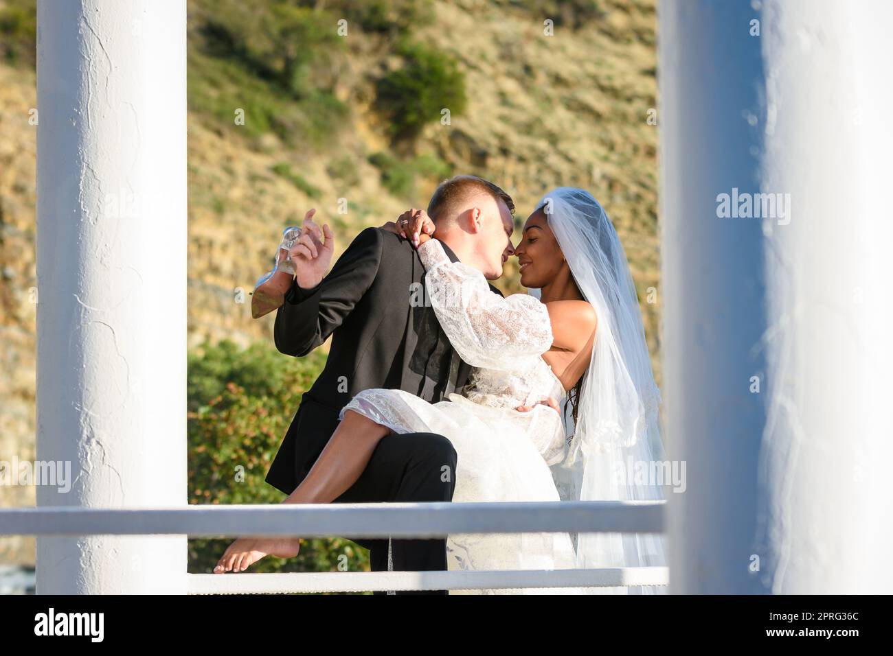 Junge schöne interracial Jungvermählte küssen im Pavillon Stockfoto
