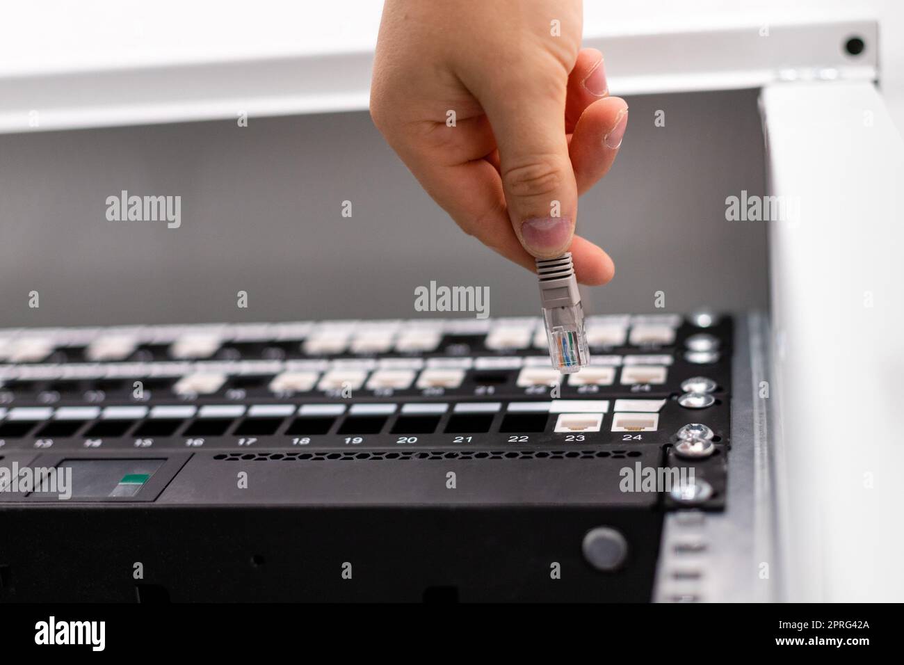 IT-Berater verbindet Netzwerkkabel mit dem Switch im Rechenzentrum. Stockfoto