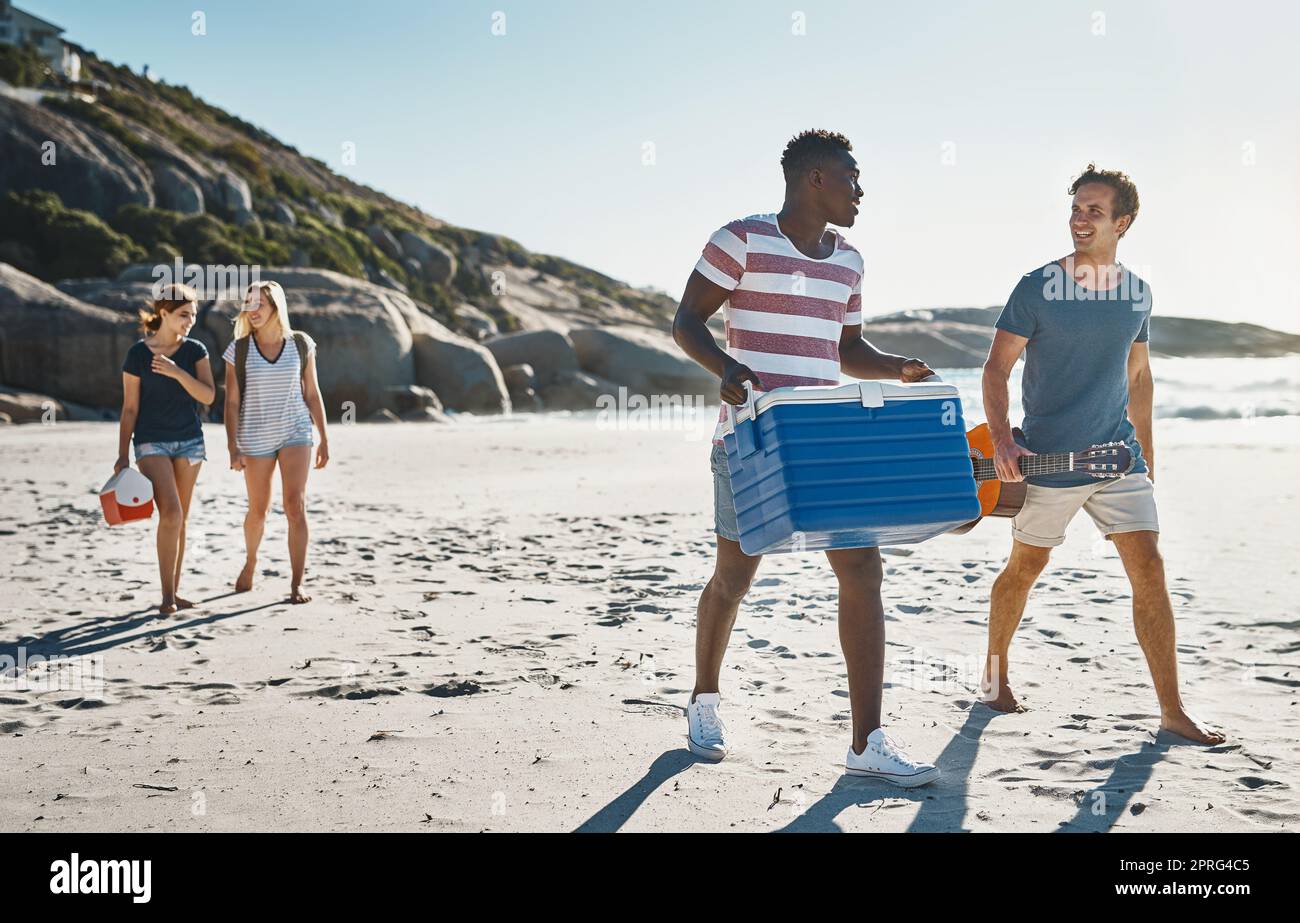 Wir freuen uns auf ein kaltes Bier am Strand. Eine Gruppe junger Freunde, die an einem sonnigen Tag am Strand spazieren gehen. Stockfoto