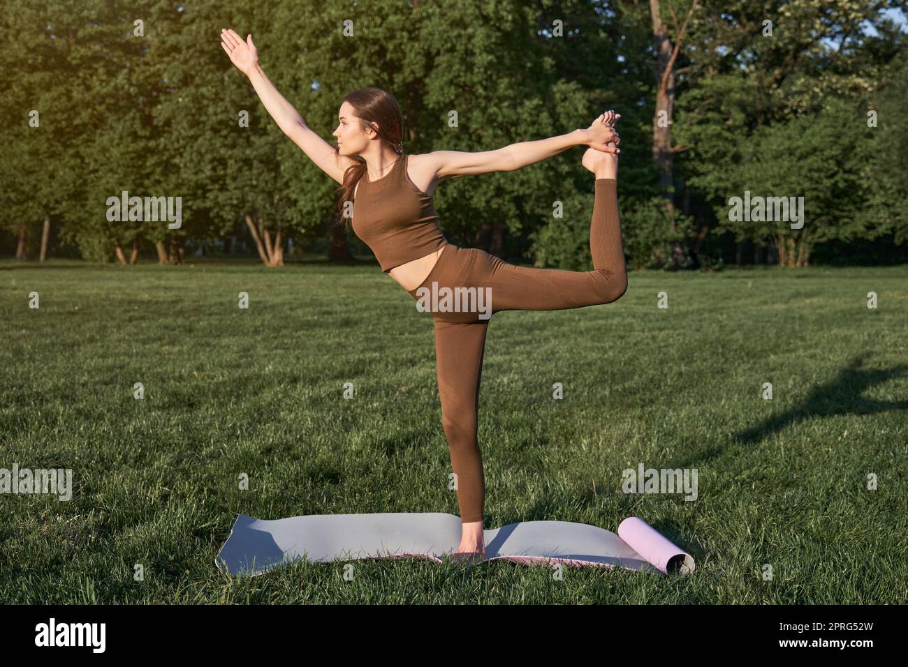 Eine junge Frau praktiziert Yoga in einem Stadtpark, während sie in einer Kriegerpose steht. Stockfoto