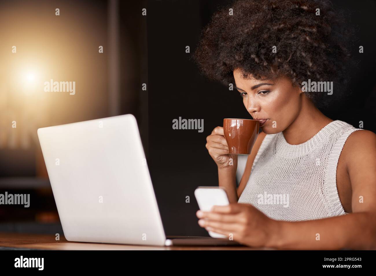 Kaffee so gut, sogar der Chef trinkt ihn. Eine junge Geschäftsbesitzerin, die einen Laptop benutzt, während sie in ihrem Café sitzt. Stockfoto