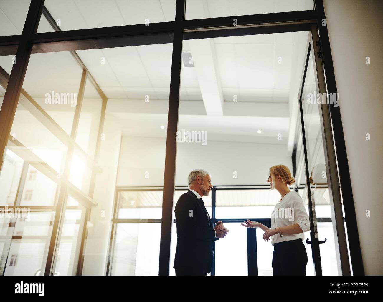 Auf der Suche nach Rat von ihrem Mentor. Zwei Geschäftsleute, die im Büro stehen, sprechen. Stockfoto