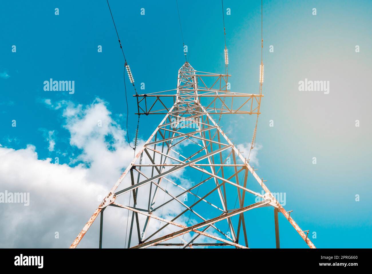 Hochspannungsturm mit Stromübertragungsleitungen gegen blauen Himmel Stockfoto
