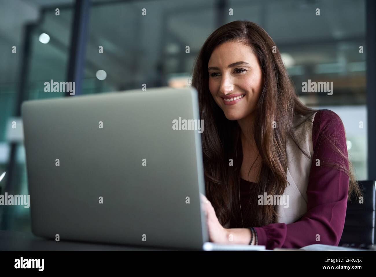 Zu wissen, wie Sie sich selbst bewerben können, ist für Ihre Karriere von entscheidender Bedeutung... eine Geschäftsfrau, die mit ihrem Laptop an ihrem Schreibtisch sitzt. Stockfoto