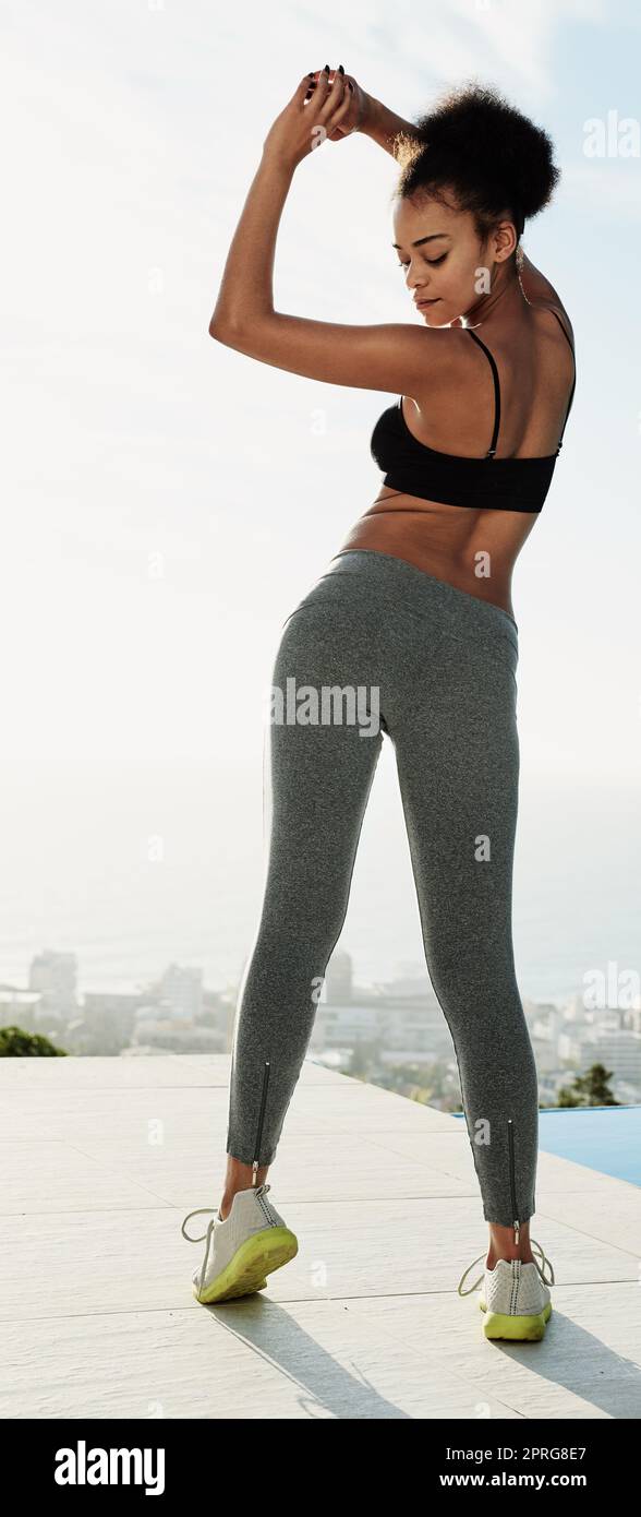 Ihr Körper spiegelt Ihren Lebensstil wider. Rückansicht einer sportlichen jungen Frau, die sich vor dem Sport ausdehnt. Stockfoto