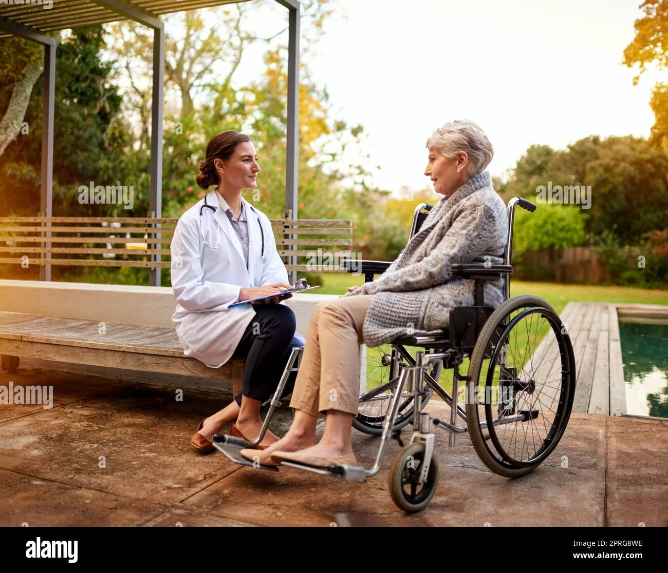 Jeder Patient verdient Mitgefühl. Eine junge Ärztin und ihre ältere Patientin reden, während sie draußen sitzen. Stockfoto