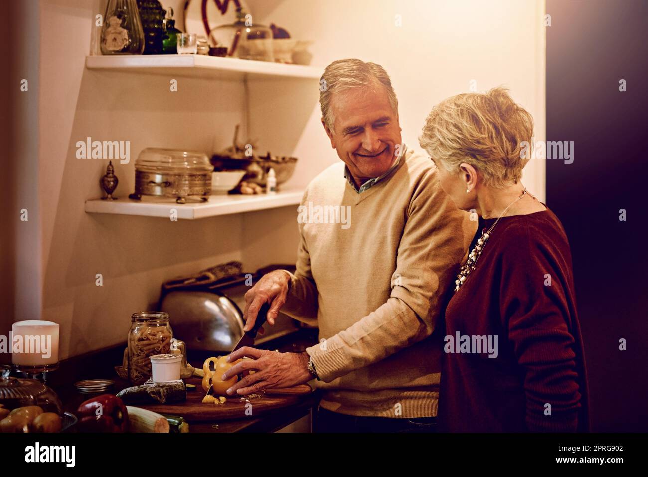 Weißt du, ich küsse mich genauso gut wie ich koche. Eine ältere Frau beobachtete ihren Mann, wie er in ihrer Küche eine Mahlzeit zubereitete. Stockfoto