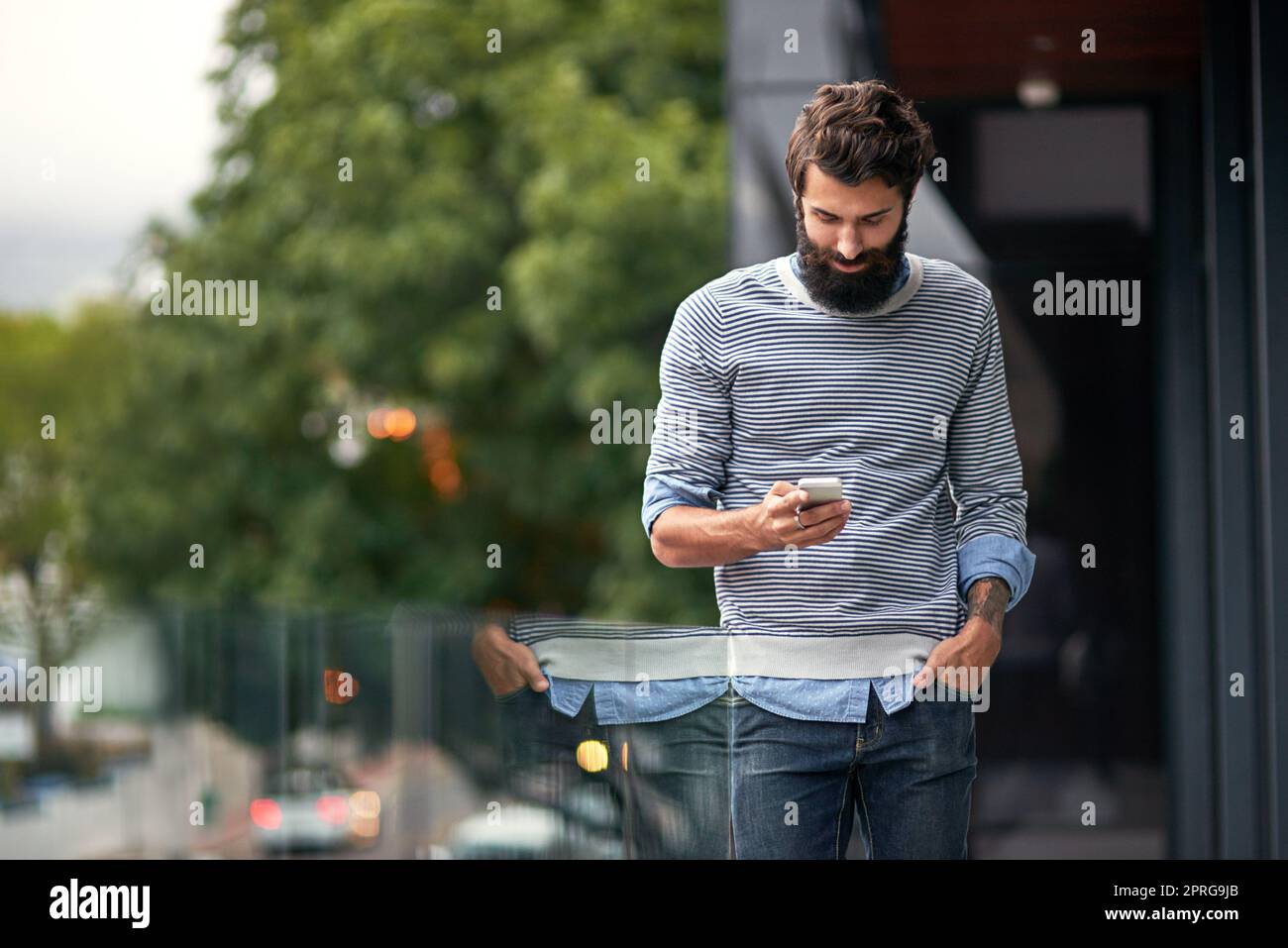 Treffen wir uns nach der Arbeit. Eine junge kreative SMS auf einem Handy draußen. Stockfoto