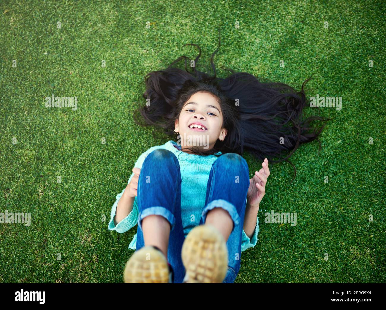 Der Inbegriff einer unbeschwerten Kindheit. Porträt eines glücklichen kleinen Mädchens, das draußen auf dem Rasen spielt. Stockfoto