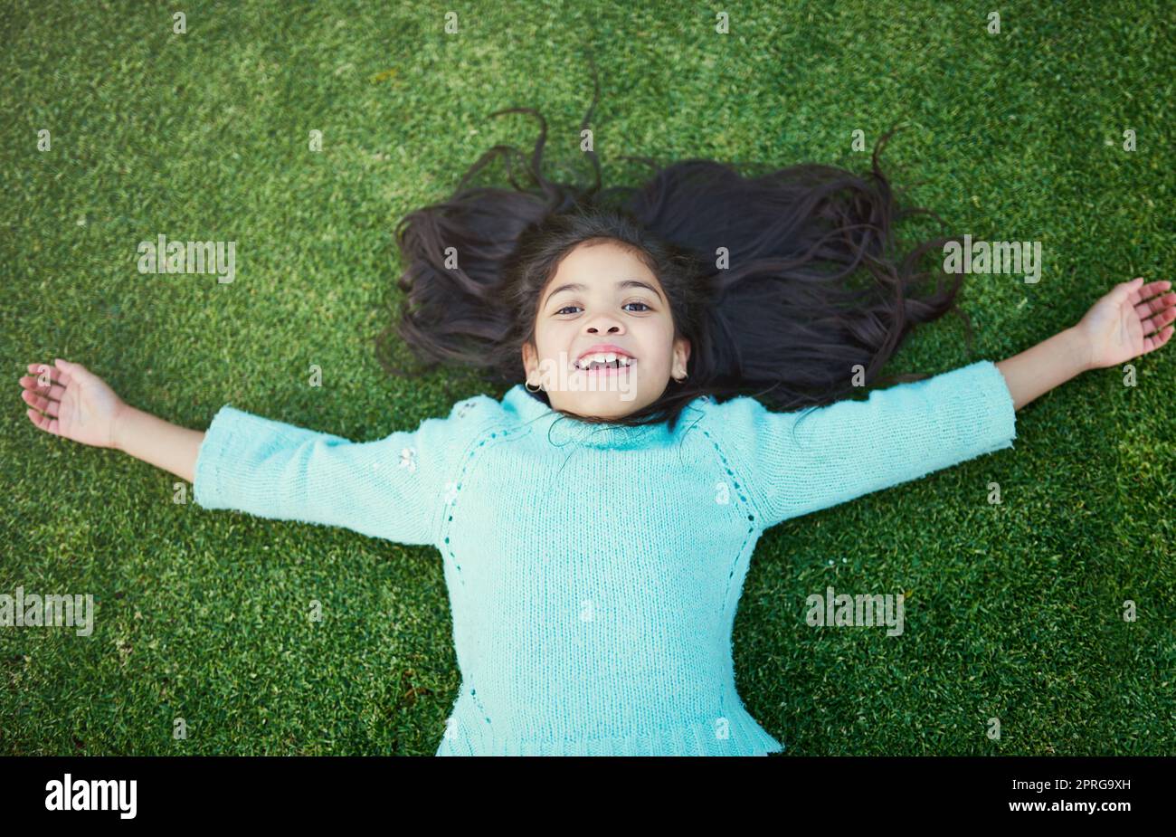 Tagelang Glück. Porträt eines glücklichen kleinen Mädchens, das draußen auf dem Rasen spielt. Stockfoto