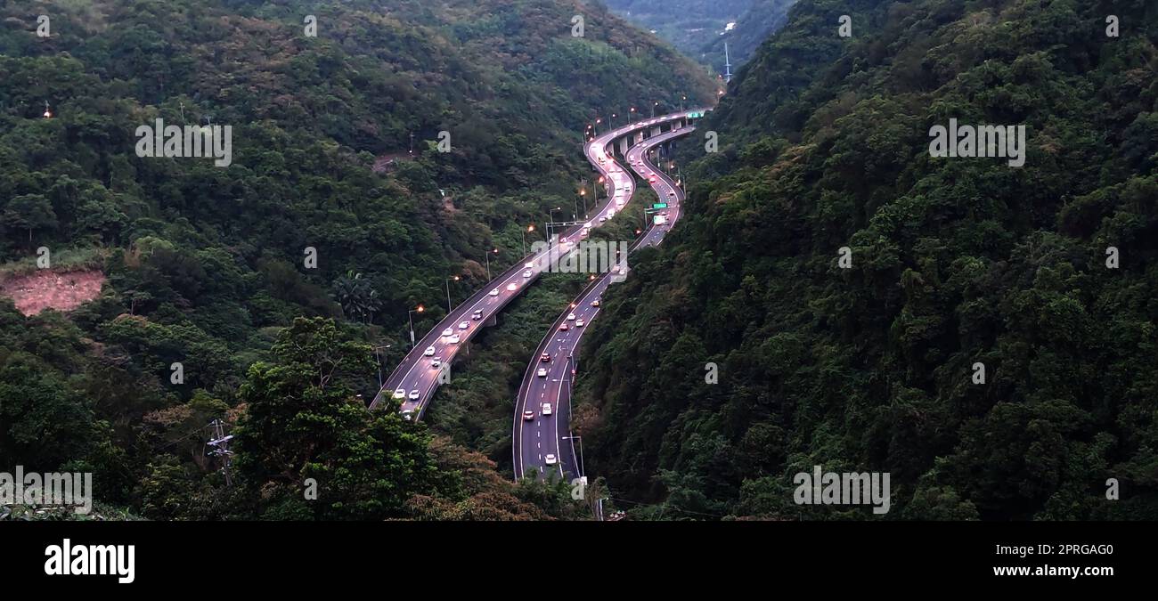 Kurvenreiche Autobahn durch die grünen Reisfelder mit Häusern, die über die Ebene in Yilan, Taiwan verstreut sind  Luftaufnahme des National Freeway Nr. 5, Taipei-Ilan Section in Ilan, Taiwan, Asien Stockfoto