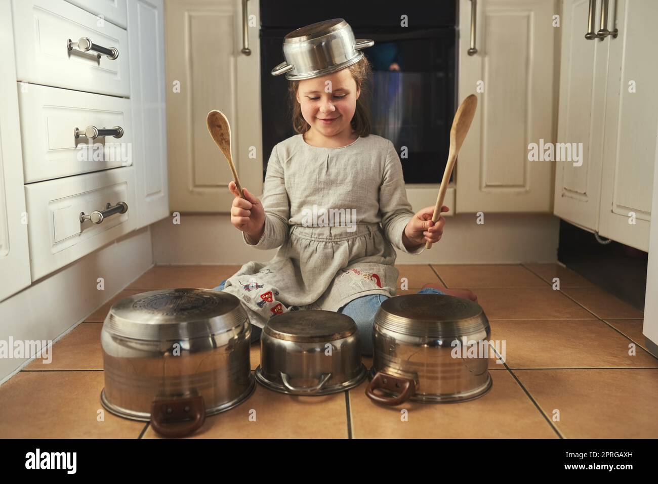 Shes ein Rockstar in der Herstellung. Ein kleines Mädchen Schlagzeug auf einem Satz von Töpfen in der Küche spielen. Stockfoto