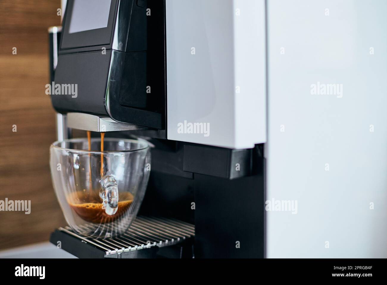 Nahaufnahme des duftenden, heißen Espressos, der aus der Kaffeemaschine ausgegossen wird. Stockfoto