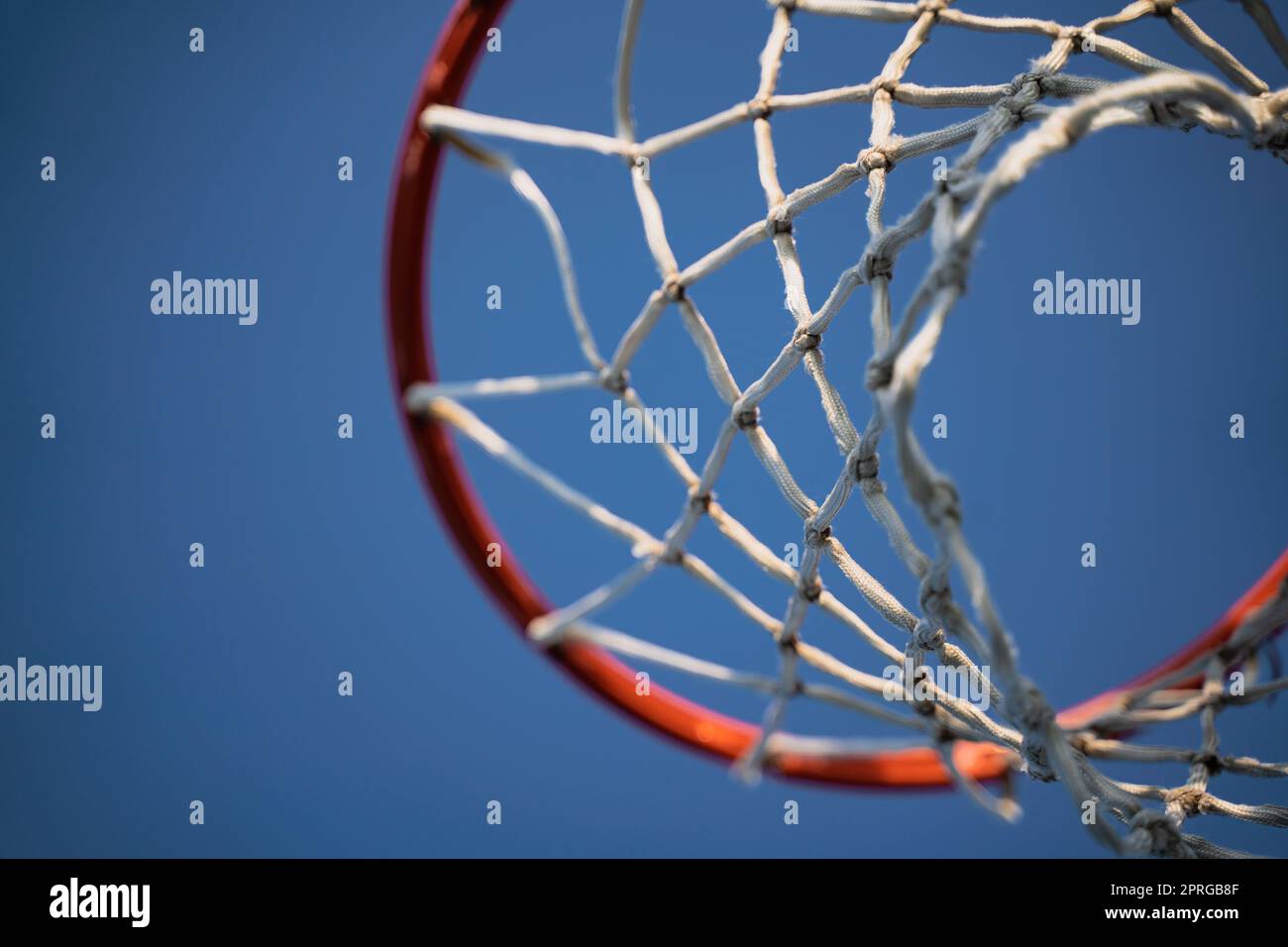 Nahaufnahme des Basketballkorbs im Freien mit weißem Seil, Blick von unten auf einen blauen Himmel mit Copyspace Stockfoto