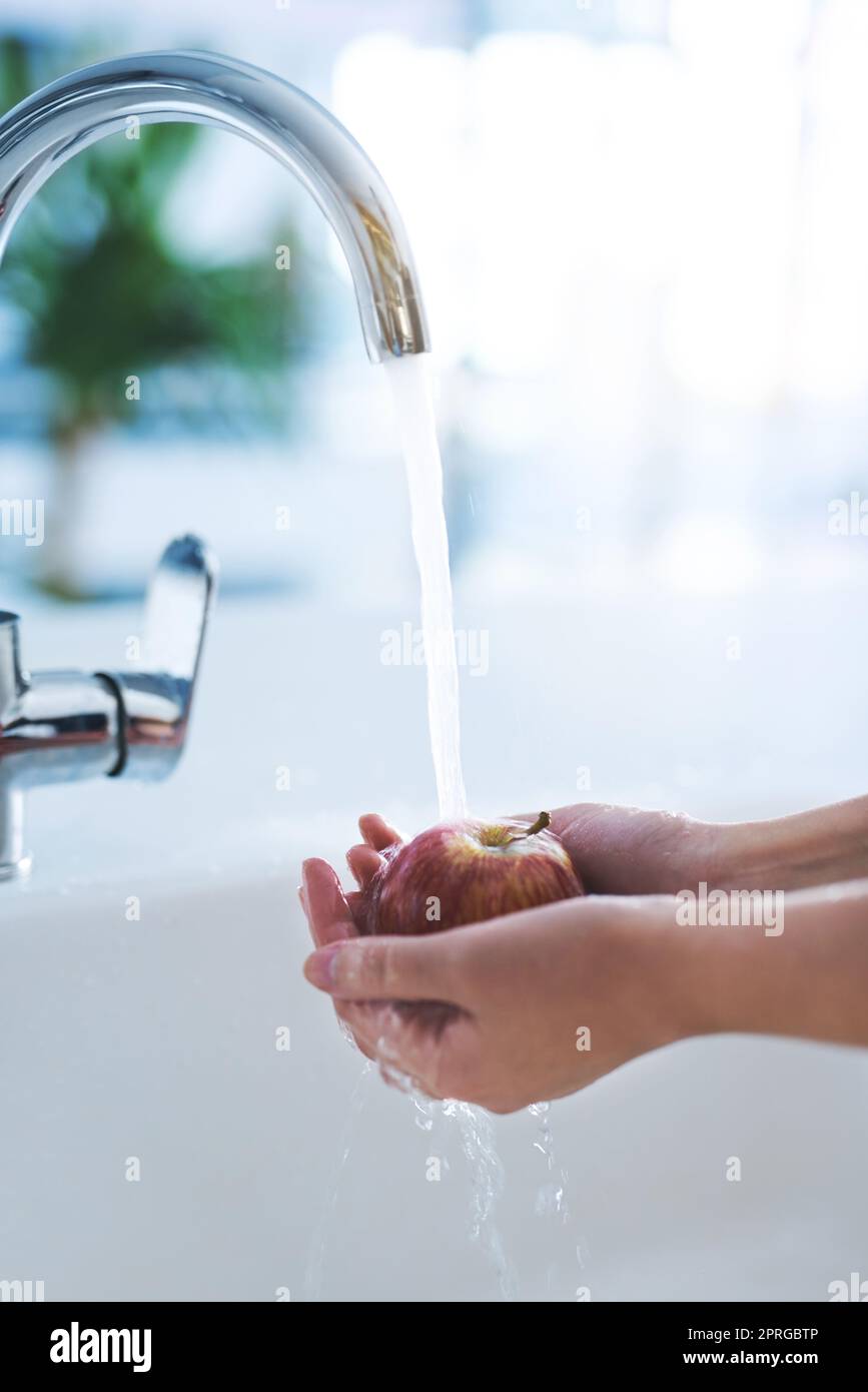 Gesund und nahrhaft. Eine Person, die einen Apfel am Wasserhahn wäscht. Stockfoto